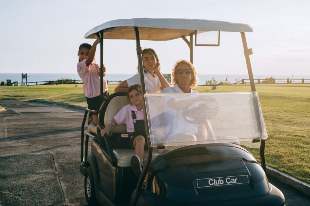 A family of four relaxing on a golf cart in a scenic outdoor setting by the sea.